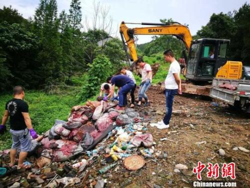 在举报人员的指引下，执法调查人员发现路边斜坡处数十只沁着斑驳的红色、蓝色的编织袋堆积如山。金华市环保局提供